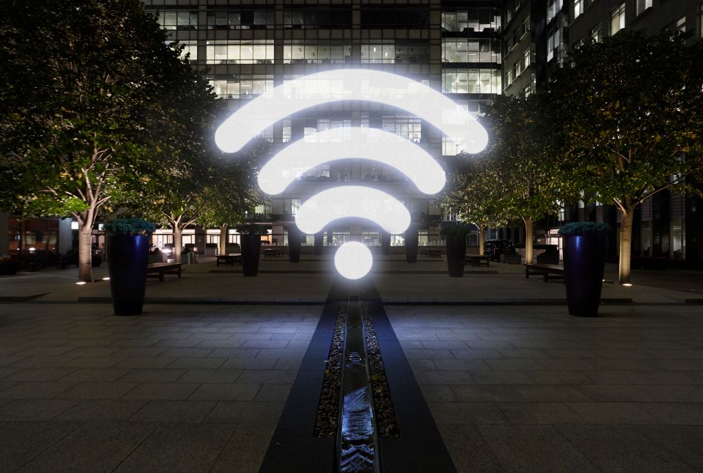 Glowing wifi icon in city street at night, London, UK